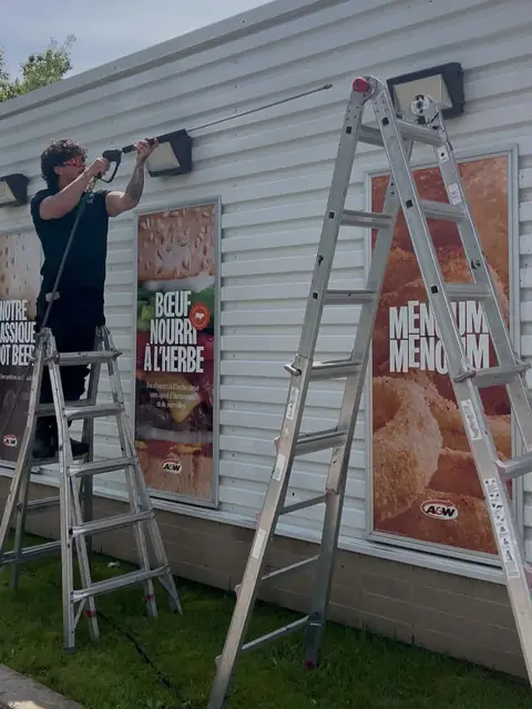 Pressure washing an exterior wall from a ladder