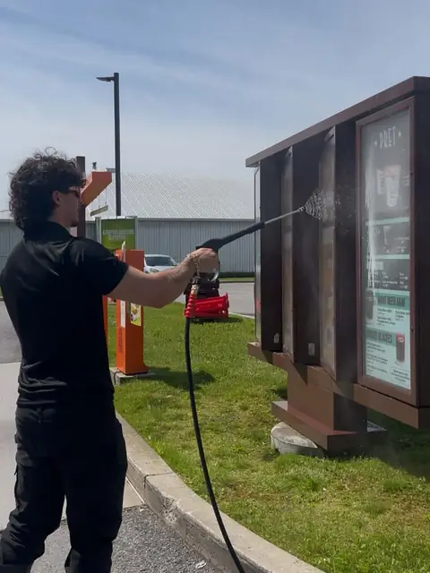 One of the owners pressure-washing an outdoor sign