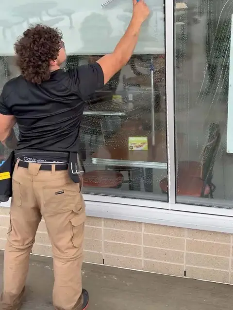 Cleaning a storefront window with a squeegee