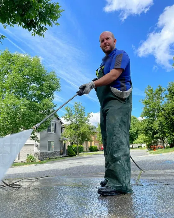 Travailleur utilisant un laveur à pression dans une rue résidentielle ensoleillée