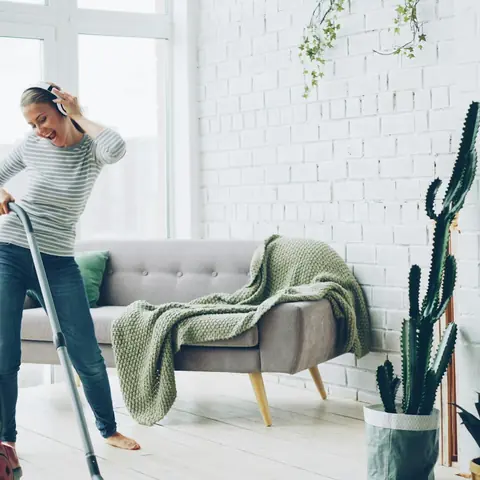 Femme passant l’aspirateur dans un salon lumineux
